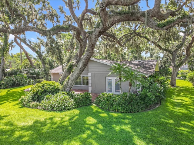 504 Banning Beach Rd, Tavares, FL 32778 - view of side of home with a lawn, stucco siding, and french doors