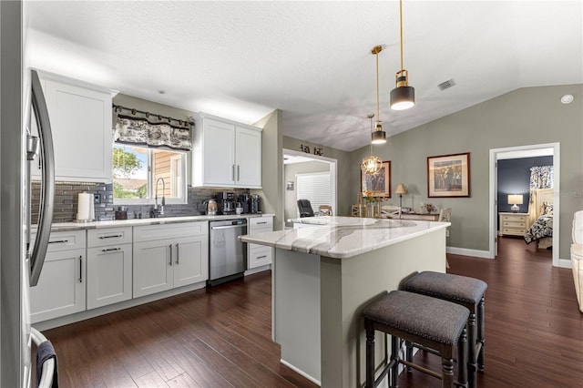 9790 SE 175th St, Summerfield, FL 34491 - kitchen featuring appliances with stainless steel finishes, a kitchen island, backsplash, a kitchen bar, and vaulted ceiling