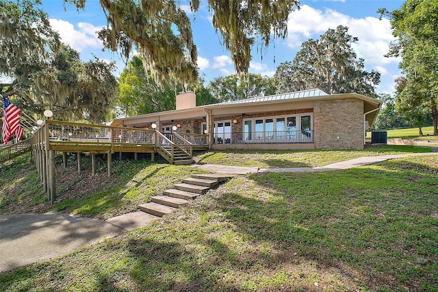 13033 SE 158th Ln, Weirsdale, FL 32195 - single story home with a chimney, a front yard, a wooden deck, stairs, and brick siding