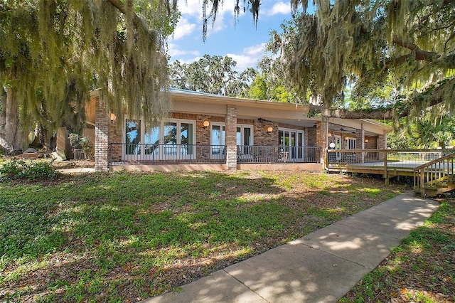13033 SE 158th Ln, Weirsdale, FL 32195 - rear view of house featuring brick siding, a deck, and french doors