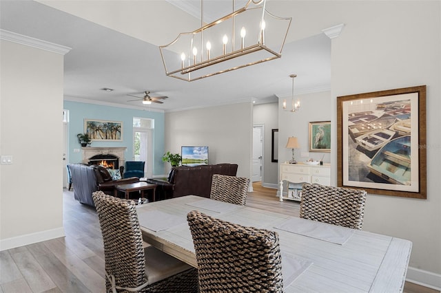 6136 Lake Emma Rd, Groveland, FL 34736 - dining room with light wood-type flooring, crown molding, a tiled fireplace, a chandelier, and a ceiling fan