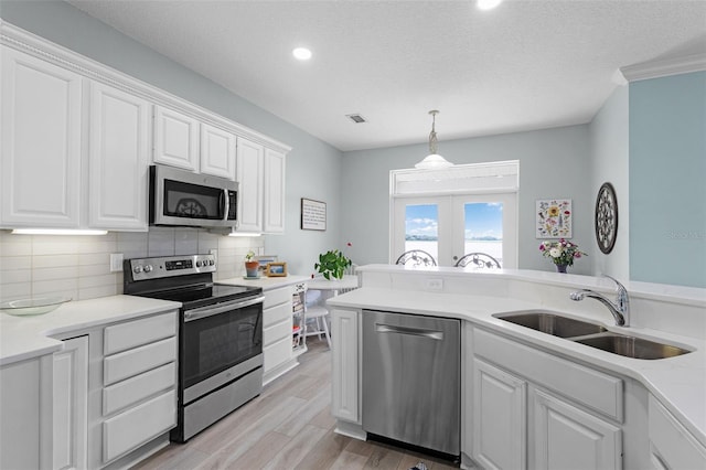 6136 Lake Emma Rd, Groveland, FL 34736 - kitchen with stainless steel appliances, white cabinetry, backsplash, light wood finished floors, and light countertops