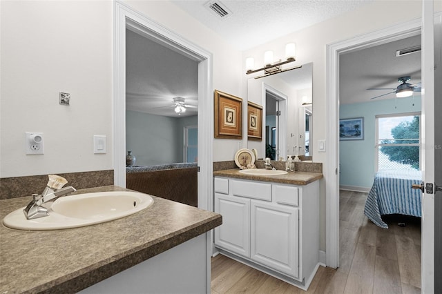 6136 Lake Emma Rd, Groveland, FL 34736 - ensuite bathroom featuring ceiling fan, two vanities, wood finished floors, and a textured ceiling
