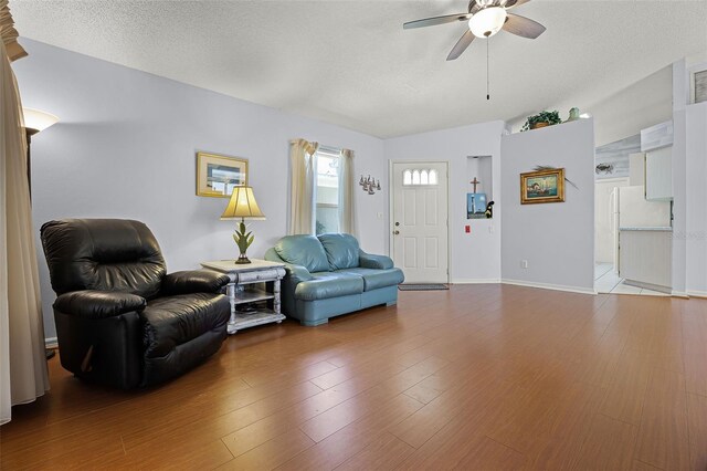5507 Laver St, Leesburg, FL 34748 - living room featuring a ceiling fan, vaulted ceiling, a textured ceiling, and wood finished floors