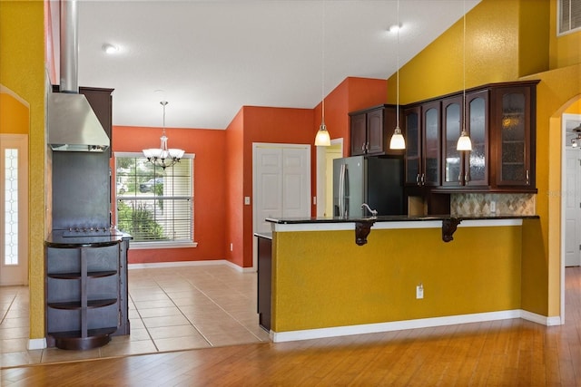 5729 Bible Camp Rd, Groveland, FL 34736 - kitchen featuring vaulted ceiling, stainless steel fridge, a kitchen bar, a chandelier, and glass insert cabinets