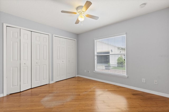 5729 Bible Camp Rd, Groveland, FL 34736 - unfurnished bedroom featuring multiple closets, light wood-style floors, and a ceiling fan