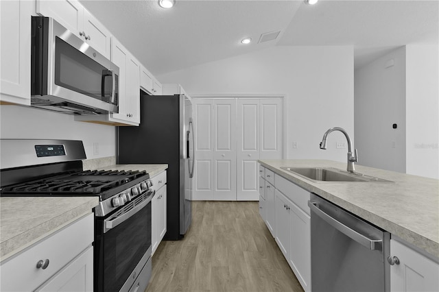 3283 Dawn Pl, The Villages, FL 32163 - kitchen with stainless steel appliances, vaulted ceiling, light countertops, light wood-style flooring, and white cabinets