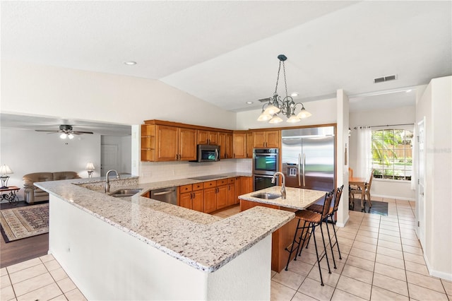 81 N Carol Ave, Mascotte, FL 34753 - kitchen with appliances with stainless steel finishes, brown cabinetry, a peninsula, light tile patterned floors, and vaulted ceiling