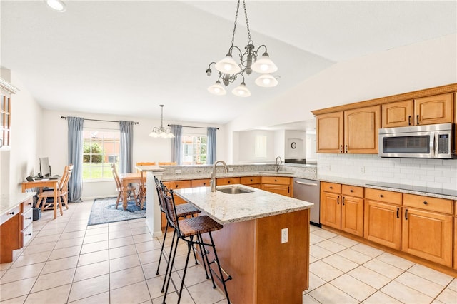 81 N Carol Ave, Mascotte, FL 34753 - kitchen with stainless steel appliances, a chandelier, vaulted ceiling, a breakfast bar area, and light stone countertops