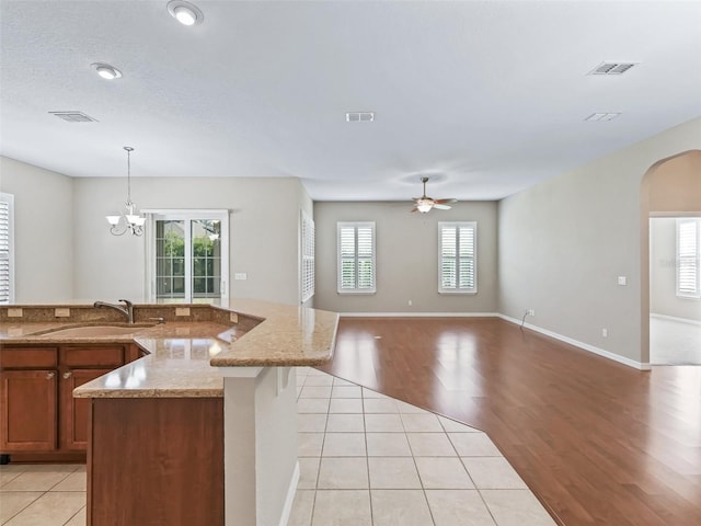 10927 SE 168th Loop, Summerfield, FL 34491 - kitchen with arched walkways, a ceiling fan, light tile patterned flooring, brown cabinets, and pendant lighting