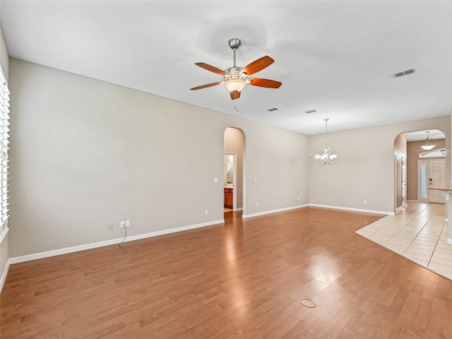10927 SE 168th Loop, Summerfield, FL 34491 - unfurnished room featuring arched walkways, a ceiling fan, light wood-style flooring, and a chandelier