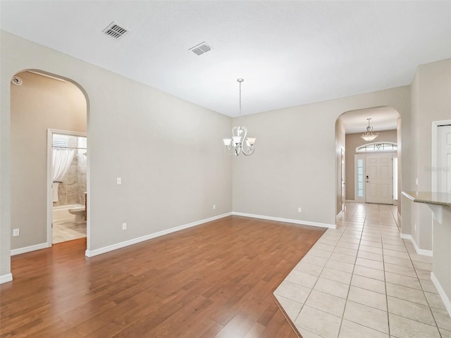 10927 SE 168th Loop, Summerfield, FL 34491 - empty room featuring arched walkways, light wood-type flooring, healthy amount of natural light, and a chandelier