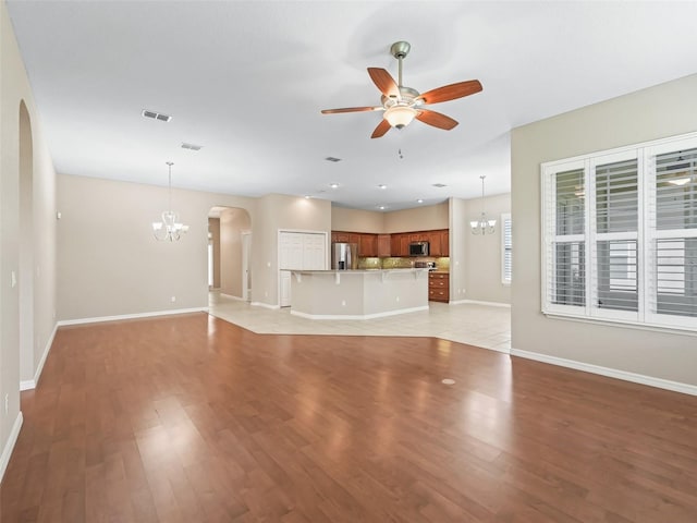 10927 SE 168th Loop, Summerfield, FL 34491 - unfurnished living room featuring arched walkways, a chandelier, ceiling fan, and light wood-style floors