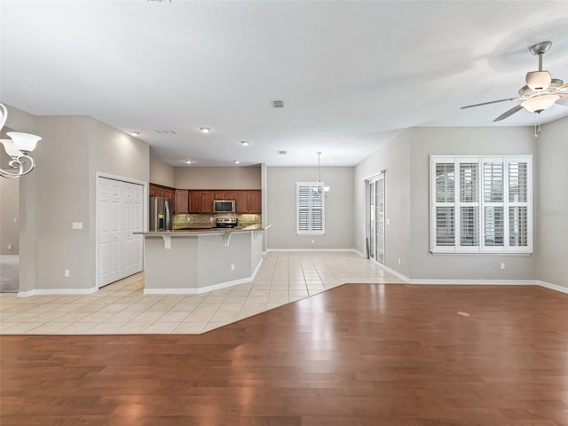 10927 SE 168th Loop, Summerfield, FL 34491 - kitchen featuring a chandelier, stainless steel appliances, open floor plan, light wood-type flooring, and a ceiling fan