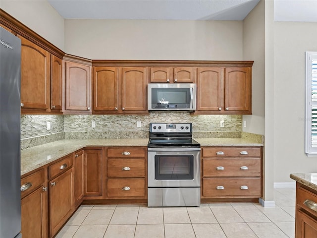 10927 SE 168th Loop, Summerfield, FL 34491 - kitchen with stainless steel appliances, decorative backsplash, light tile patterned floors, and brown cabinetry
