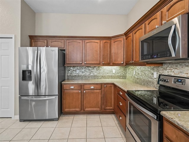 10927 SE 168th Loop, Summerfield, FL 34491 - kitchen featuring appliances with stainless steel finishes, light tile patterned floors, decorative backsplash, and light stone counters