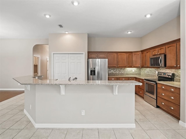 10927 SE 168th Loop, Summerfield, FL 34491 - kitchen with appliances with stainless steel finishes, light tile patterned floors, a kitchen bar, and decorative backsplash