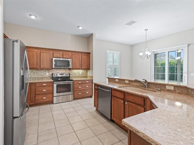 10927 SE 168th Loop, Summerfield, FL 34491 - kitchen with appliances with stainless steel finishes, brown cabinetry, a chandelier, decorative backsplash, and decorative light fixtures