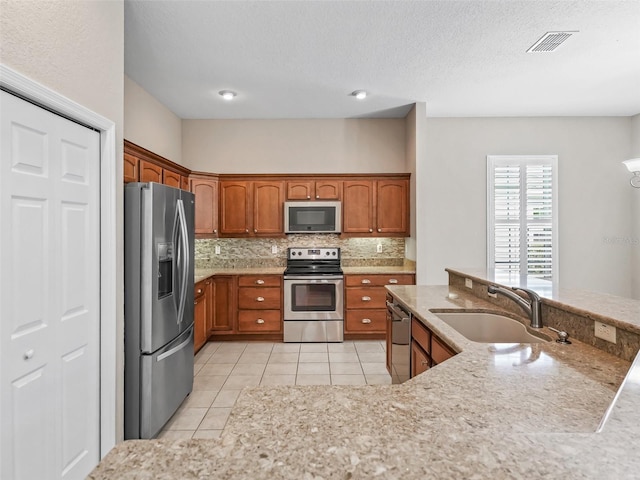 10927 SE 168th Loop, Summerfield, FL 34491 - kitchen featuring stainless steel appliances, brown cabinets, backsplash, light tile patterned floors, and a textured ceiling