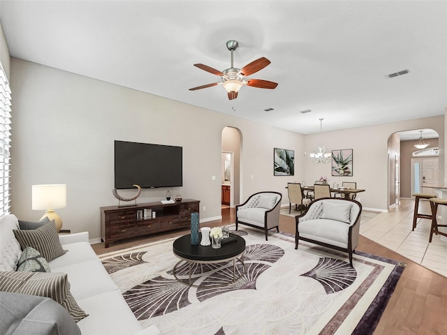 10927 SE 168th Loop, Summerfield, FL 34491 - living room featuring arched walkways, wood finished floors, a ceiling fan, and a chandelier