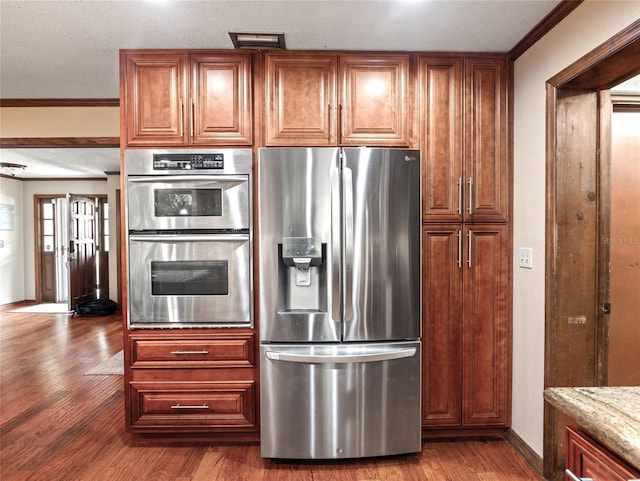 15733 Tower View Dr, Clermont, FL 34711 - kitchen with stainless steel appliances, wood finished floors, crown molding, light stone counters, and brown cabinets
