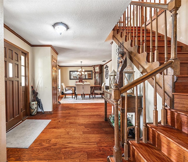 15733 Tower View Dr, Clermont, FL 34711 - foyer with stairway, wood finished floors, a chandelier, a textured ceiling, and crown molding