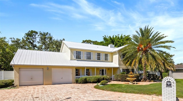15733 Tower View Dr, Clermont, FL 34711 - traditional home featuring a garage, decorative driveway, a metal roof, covered porch, and brick siding