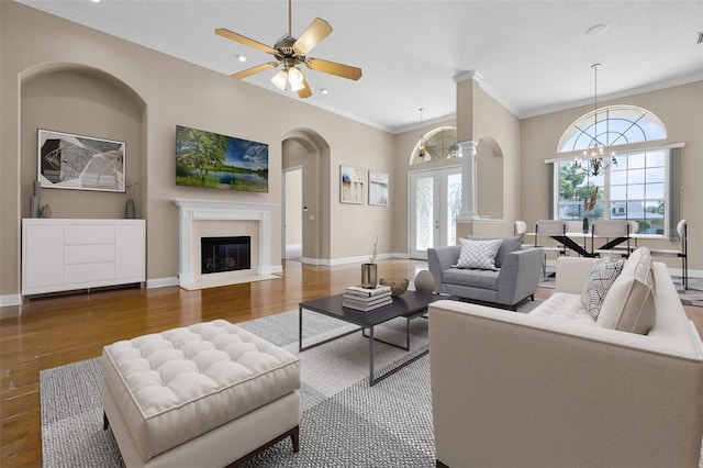 7303 Spring Mountain Ln, Yalaha, FL 34797 - living area featuring arched walkways, wood finished floors, a chandelier, a fireplace with flush hearth, and crown molding