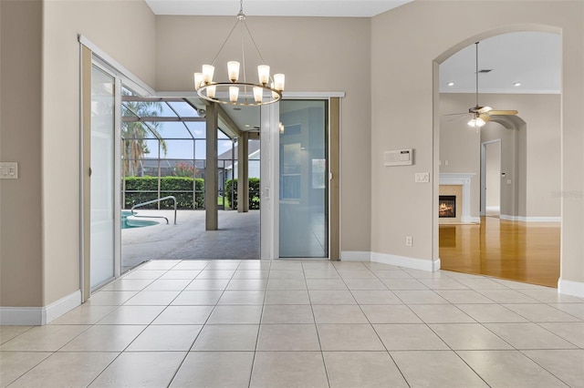 7303 Spring Mountain Ln, Yalaha, FL 34797 - unfurnished dining area featuring tile patterned flooring, a chandelier, ceiling fan, arched walkways, and a tile fireplace