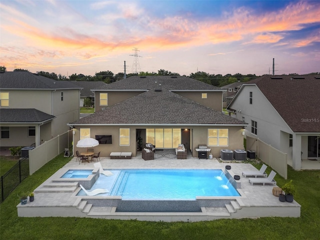 3304 Canna Lily Pl, Clermont, FL 34711 - back of house at dusk with a fenced backyard, a patio area, a shingled roof, stucco siding, and a pool with connected hot tub