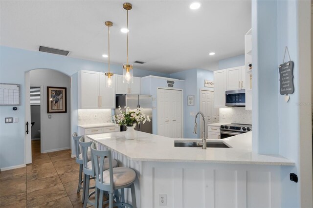 14708 Timucua Pl, Clermont, FL 34711 - kitchen with stainless steel appliances, tasteful backsplash, a peninsula, white cabinetry, and recessed lighting