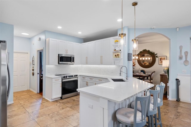 14708 Timucua Pl, Clermont, FL 34711 - kitchen with stainless steel appliances, a peninsula, a kitchen breakfast bar, backsplash, and light countertops