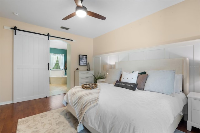 14708 Timucua Pl, Clermont, FL 34711 - bedroom with a barn door, wood finished floors, ensuite bathroom, and ceiling fan
