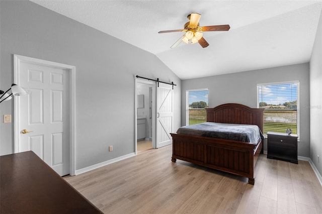 5715 Illumination Ln, Leesburg, FL 34748 - bedroom with a barn door, lofted ceiling, light wood finished floors, ensuite bath, and a ceiling fan