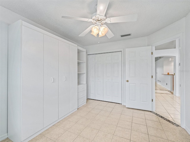 1142 W Boone Ct, The Villages, FL 32159 - unfurnished bedroom with a textured ceiling, light tile patterned floors, arched walkways, a ceiling fan, and a closet