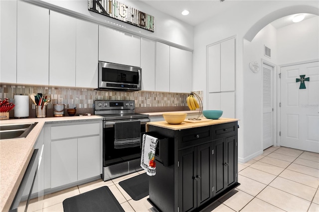 5740 Bounty Cir, Tavares, FL 32778 - kitchen featuring appliances with stainless steel finishes, dark cabinets, arched walkways, light countertops, and white cabinetry