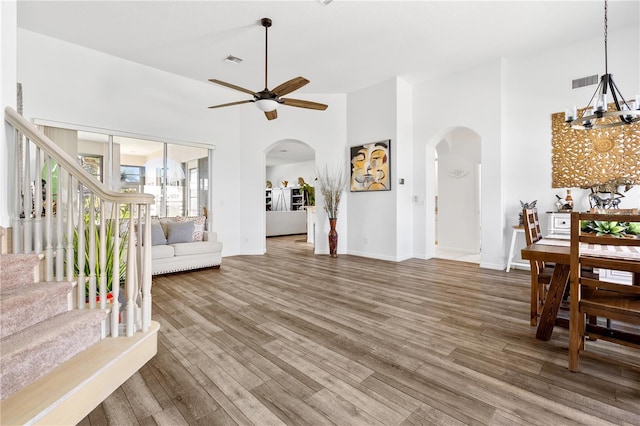 5740 Bounty Cir, Tavares, FL 32778 - living area with arched walkways, a chandelier, a ceiling fan, wood finished floors, and a towering ceiling