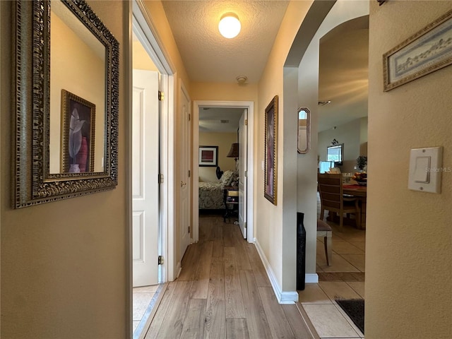 15509 Markham Dr, Clermont, FL 34714 - hallway featuring arched walkways, a textured ceiling, and light wood finished floors