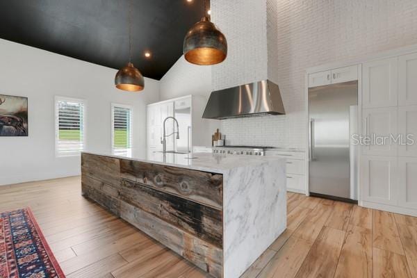 10711 County Road 561, Clermont, FL 34711 - kitchen with wall chimney exhaust hood, built in refrigerator, high vaulted ceiling, light wood finished floors, and white cabinetry