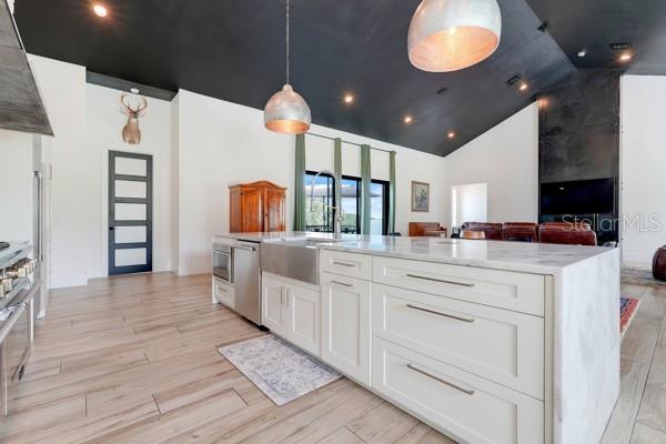 10711 County Road 561, Clermont, FL 34711 - kitchen with range hood, light wood-style floors, dishwasher, white cabinetry, and high vaulted ceiling