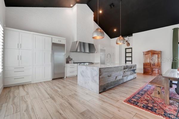 10711 County Road 561, Clermont, FL 34711 - kitchen with high vaulted ceiling, stainless steel built in fridge, range hood, white cabinets, and light wood-style flooring