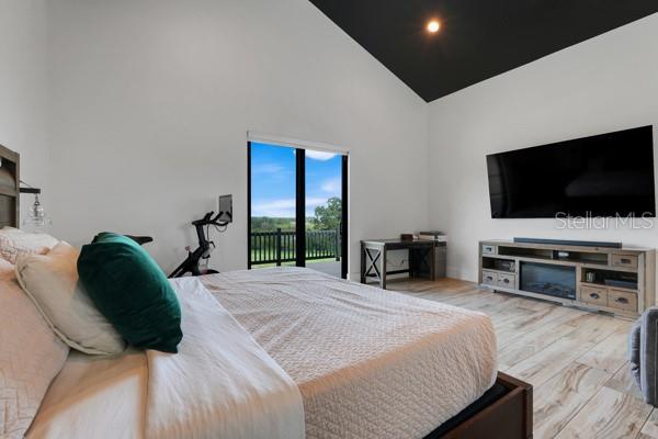 10711 County Road 561, Clermont, FL 34711 - bedroom featuring high vaulted ceiling, access to outside, and wood finished floors