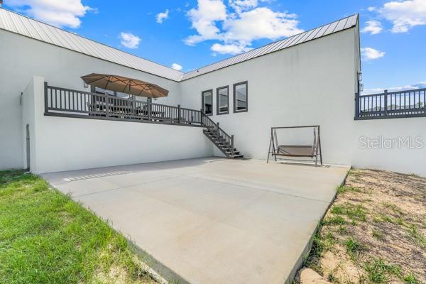 10711 County Road 561, Clermont, FL 34711 - back of house featuring stucco siding, a patio, a metal roof, stairs, and a standing seam roof