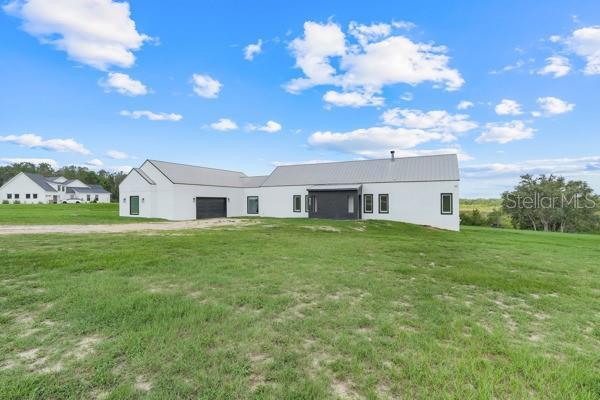 10711 County Road 561, Clermont, FL 34711 - rear view of property featuring a garage, a lawn, stucco siding, and dirt driveway