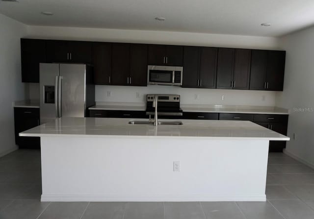1138 Calico Pointe Cir, Groveland, FL 34736 - kitchen with stainless steel appliances, a kitchen island with sink, light countertops, and light tile patterned floors