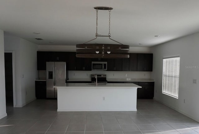 1138 Calico Pointe Cir, Groveland, FL 34736 - kitchen featuring stainless steel appliances, light countertops, light tile patterned flooring, and a center island with sink