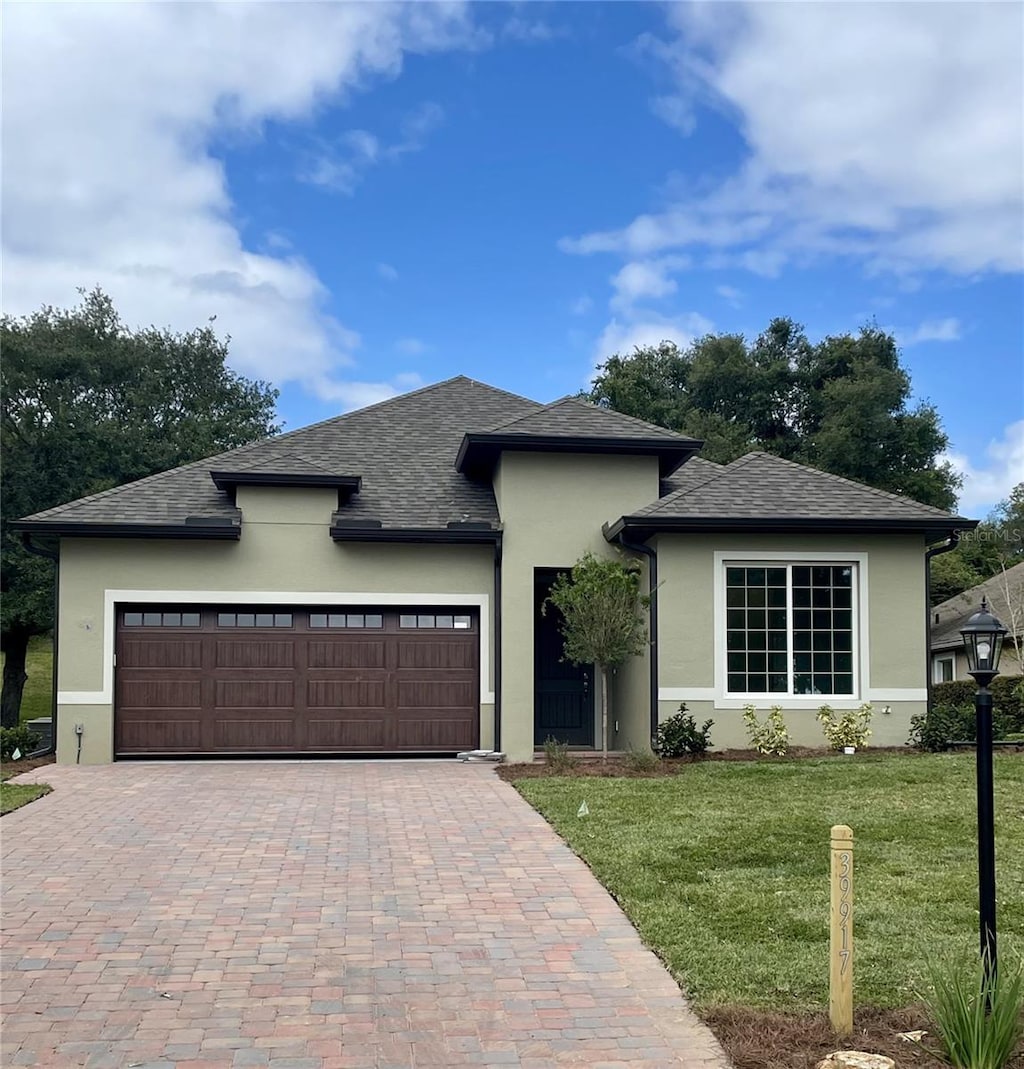 0 Sunbeam Way, Lady Lake, FL 32159 - view of front of property with stucco siding, an attached garage, a front yard, decorative driveway, and roof with shingles