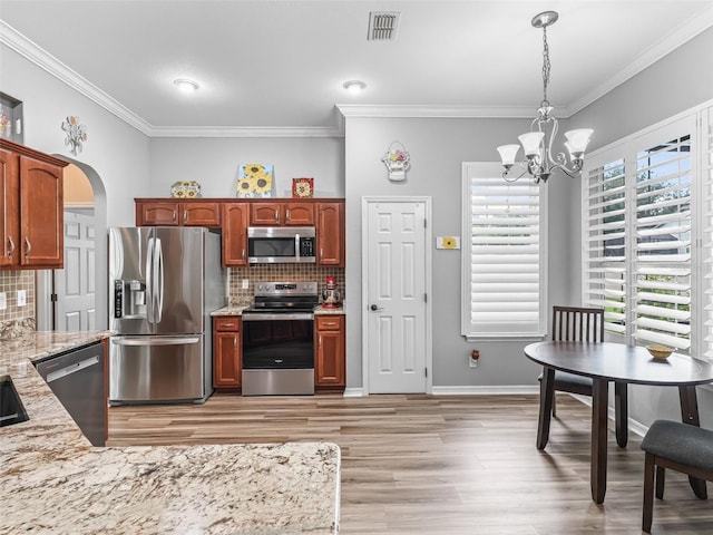 16863 SE 110th Court Rd, Summerfield, FL 34491 - kitchen with appliances with stainless steel finishes, ornamental molding, a chandelier, light wood finished floors, and decorative backsplash