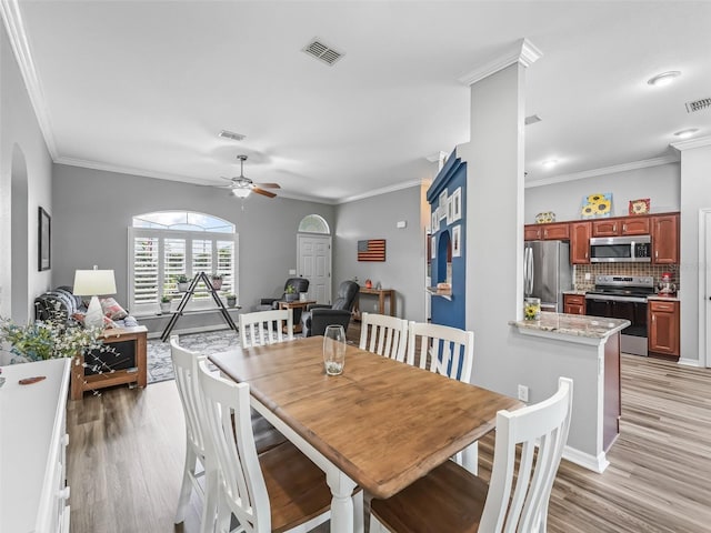 16863 SE 110th Court Rd, Summerfield, FL 34491 - dining area featuring light wood-style flooring, ceiling fan, crown molding, and arched walkways