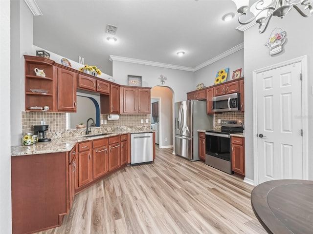 16863 SE 110th Court Rd, Summerfield, FL 34491 - kitchen featuring appliances with stainless steel finishes, crown molding, arched walkways, tasteful backsplash, and light stone counters